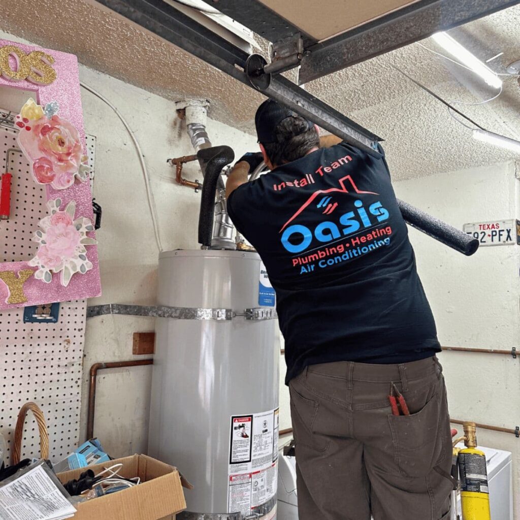 Oasis team technician working on a water heater vent pipe in a residential garage
