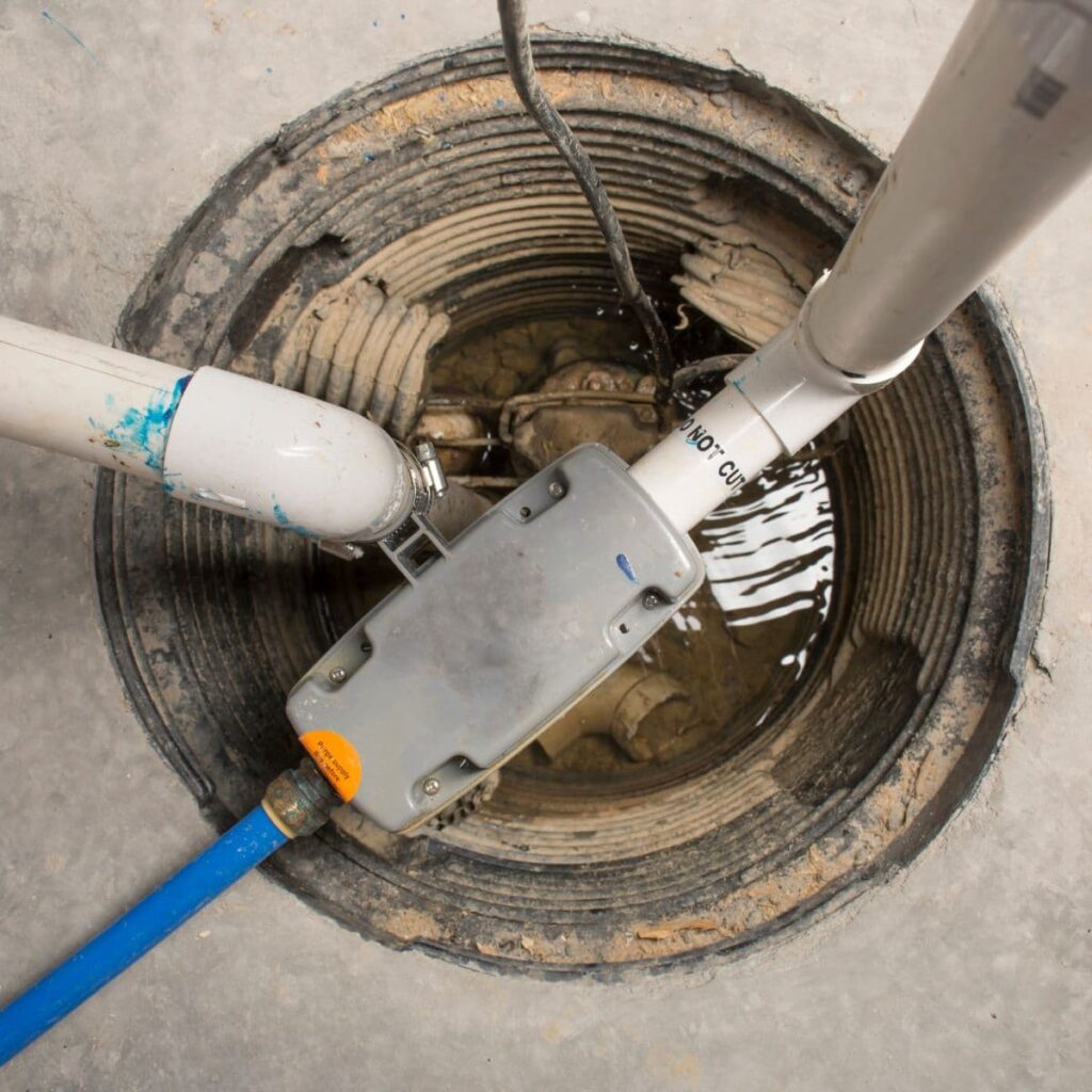 Sump pump system with connected PVC drainage pipes inside a circular basin