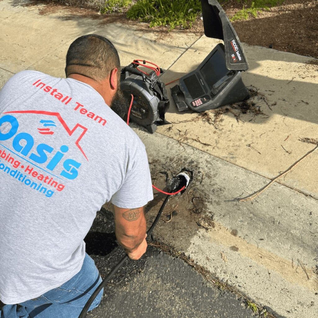 Oasis team member using a sewer inspection camera and cable to clear a drain on a residential sidewalk