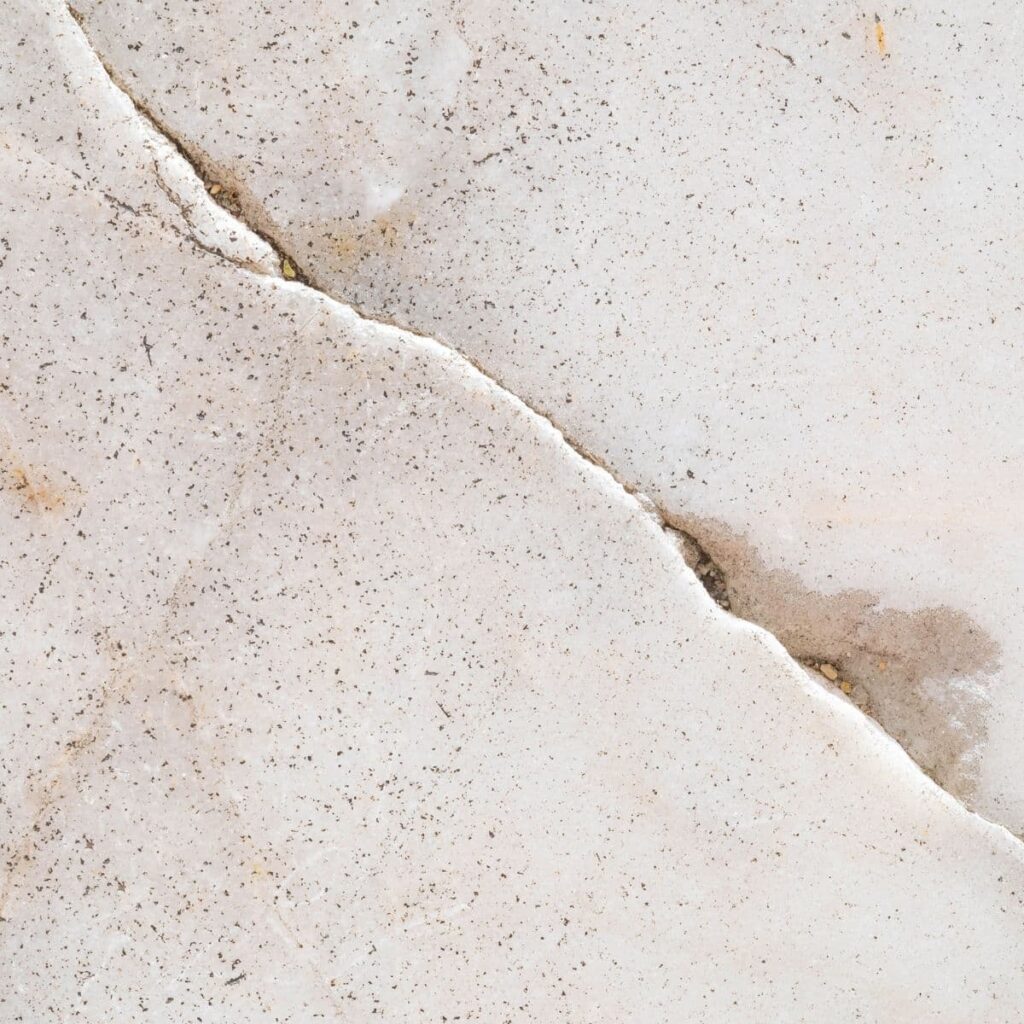 Hairline crack running through a light-colored concrete surface indicating possible foundation damage