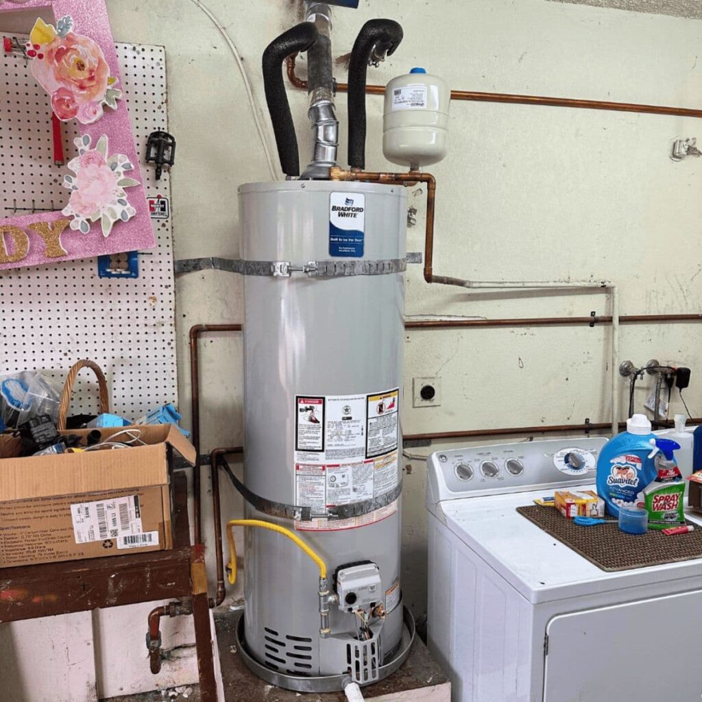 Residential gas water heater installed in a laundry room next to a washing machine