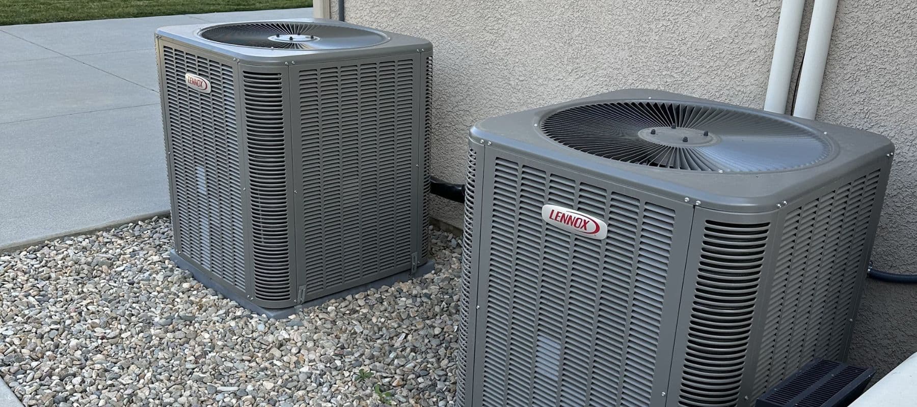 Two Lennox air conditioning units installed side-by-side on a gravel pad outside a home