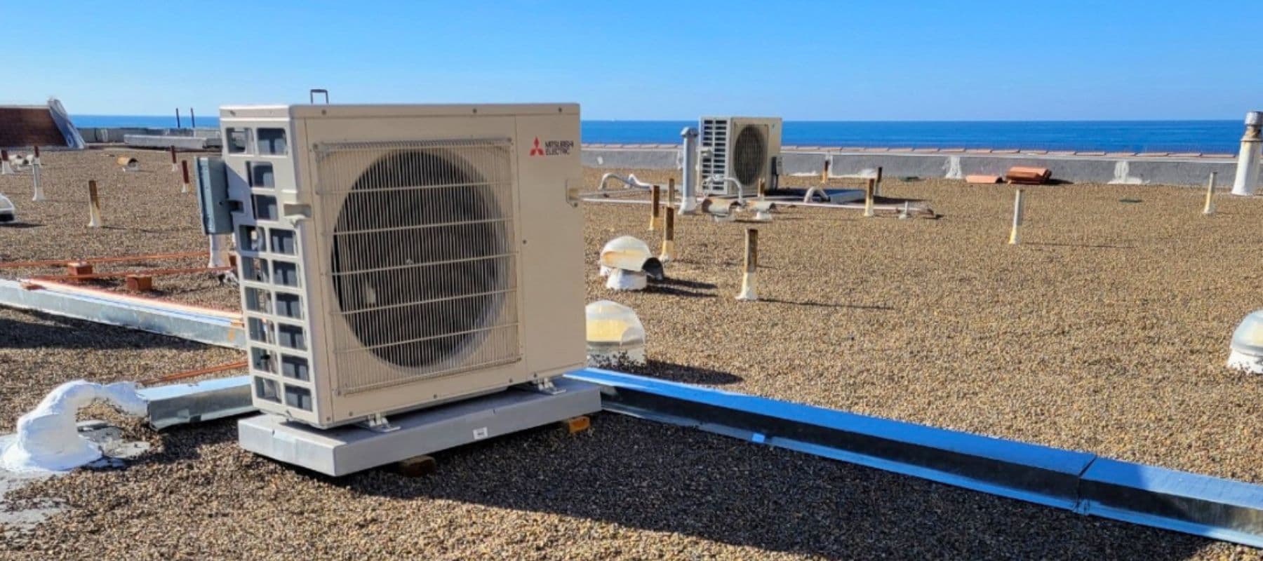Mitsubishi HVAC unit installed on a rooftop with a scenic ocean view in the background.