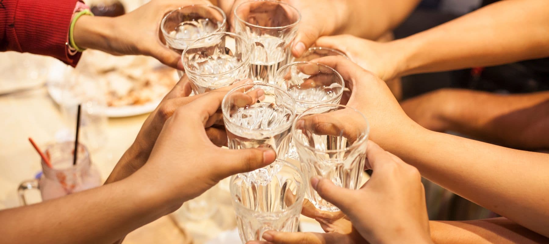 Group of people raising glasses of clear water for a celebratory toast