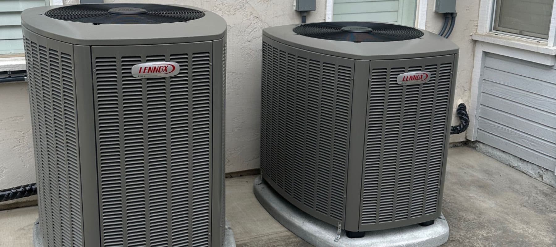 Two Lennox air conditioning units installed side-by-side on a concrete patio