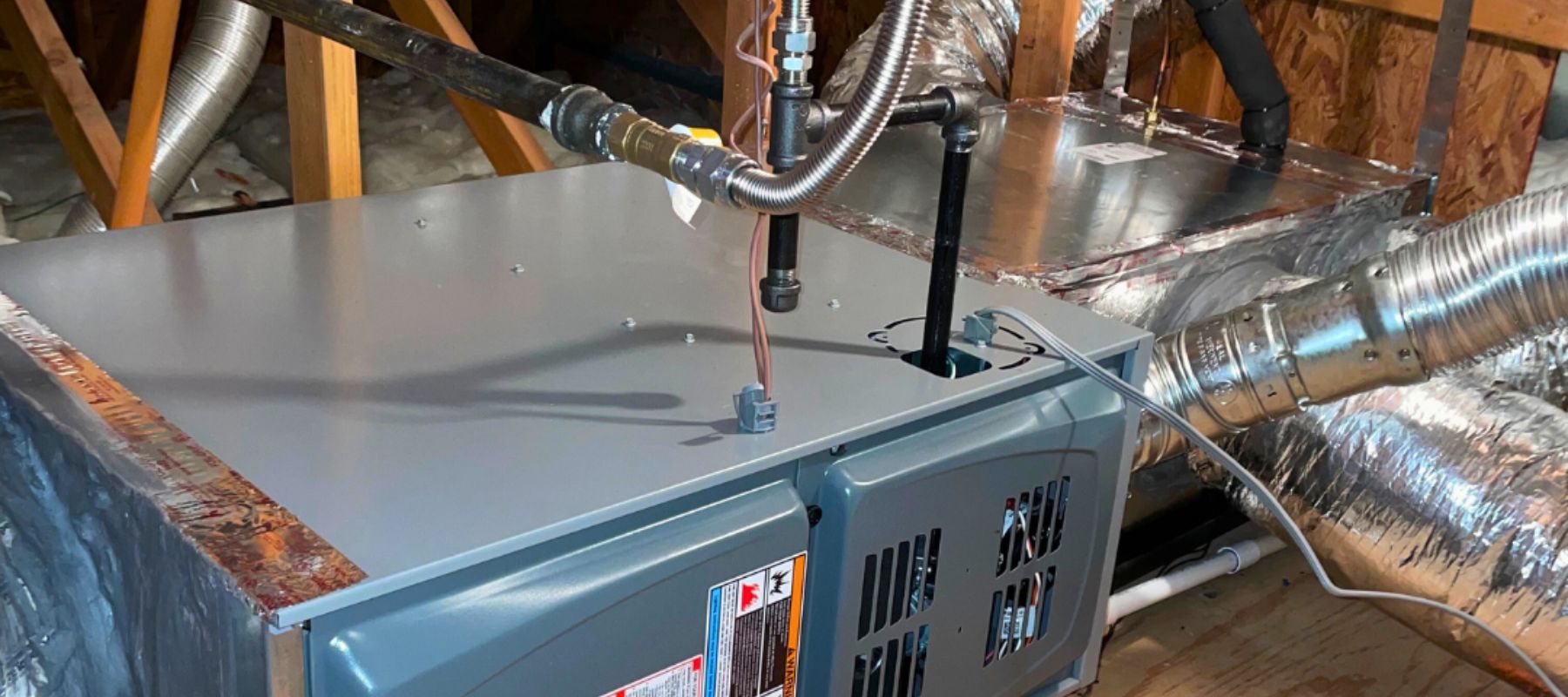 HVAC furnace unit with connected ductwork and refrigerant lines installed in an attic