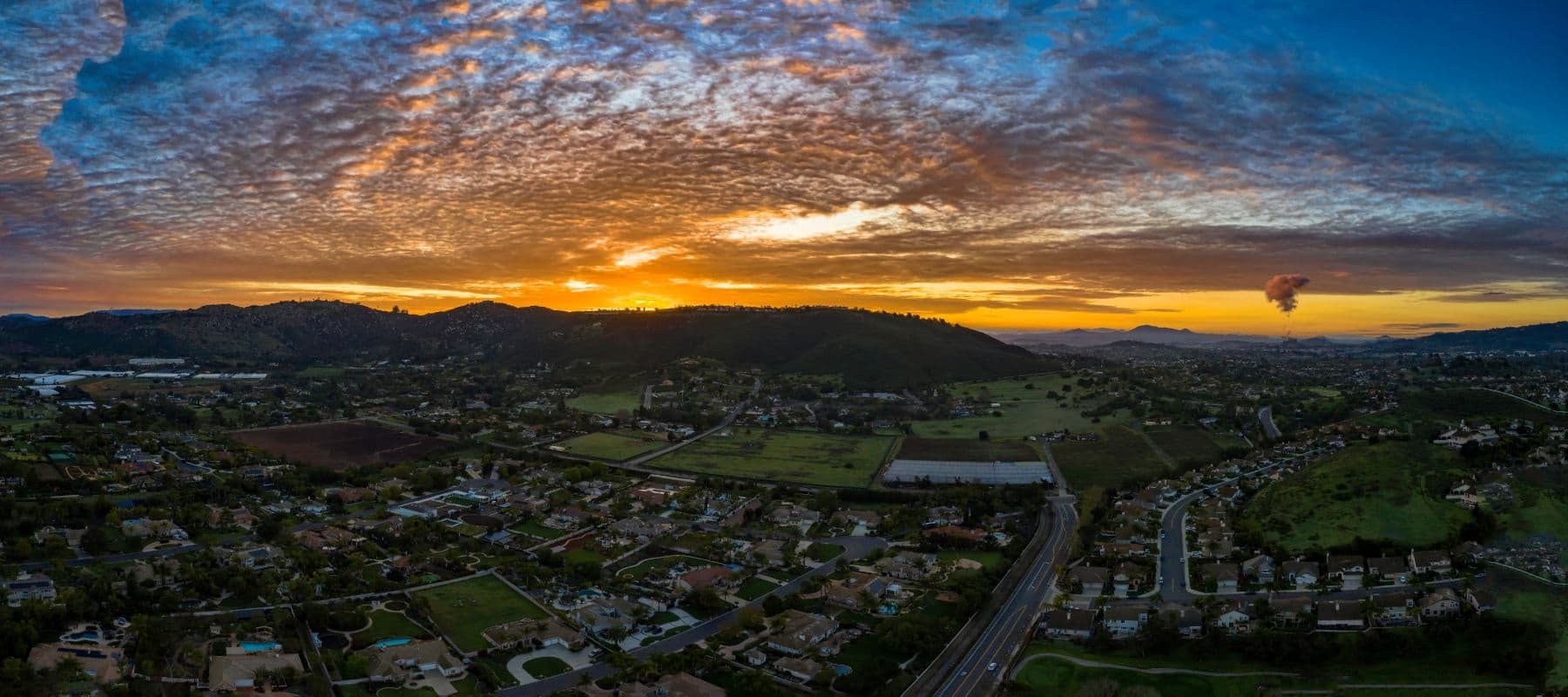Aerial view of a suburban community with rolling hills at sunset under a dramatic sky