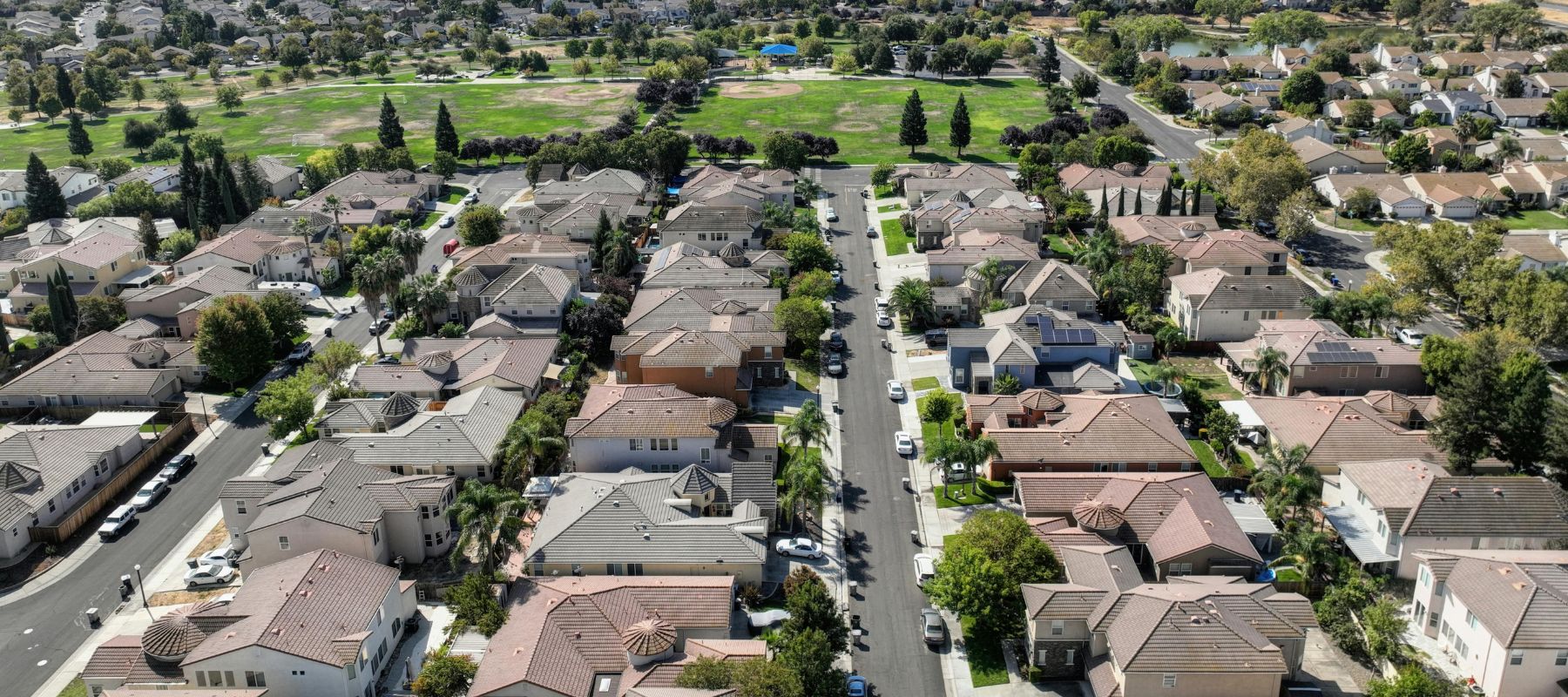 aerial view of neighborhoods with houses that have tile roofs and green grass