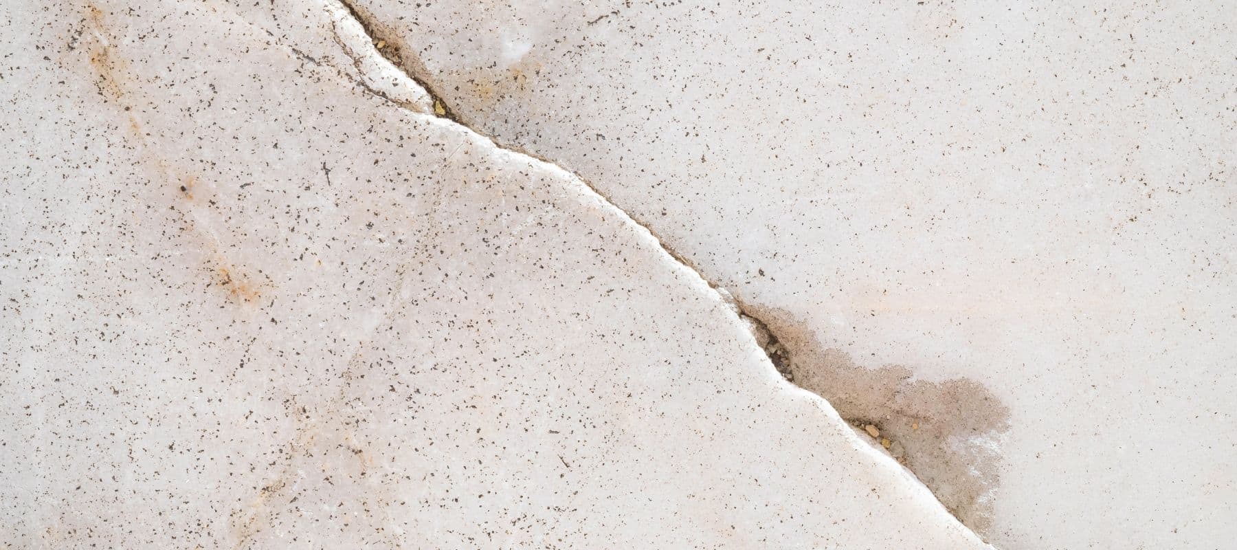 Hairline crack running through a light-colored concrete surface indicating possible foundation damage